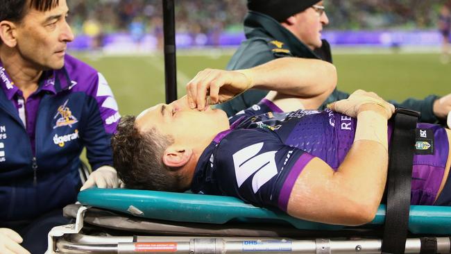 Billy Slater of the Storm is taken from the field after a tackle by Iosia Soliola of the Raiders.