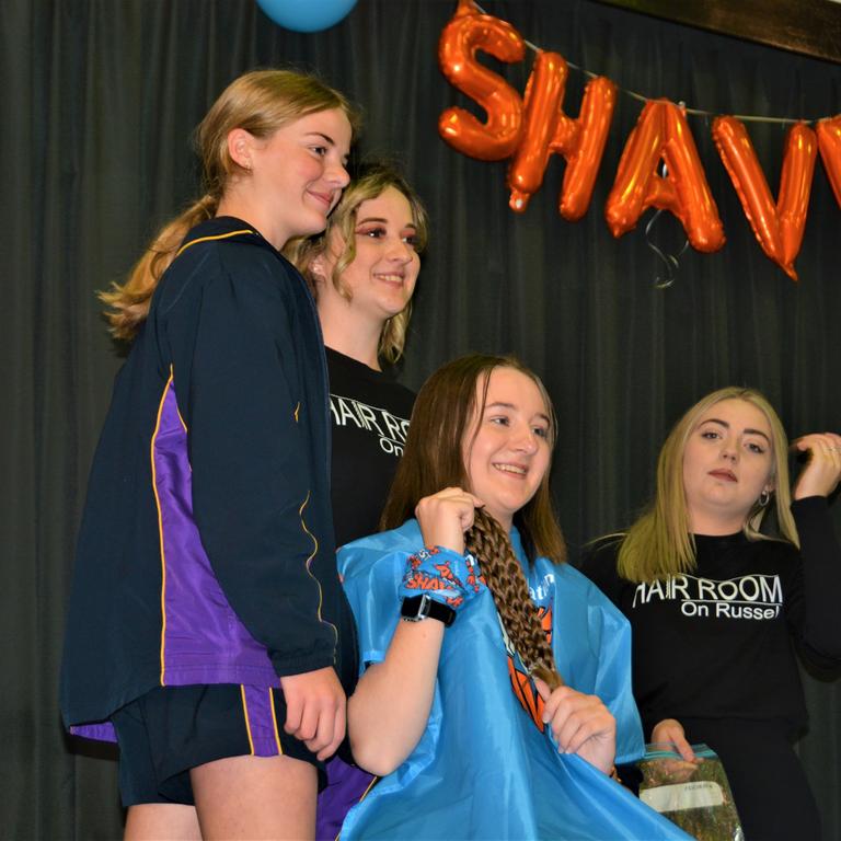 At the St Joseph's College 2023 World's Greatest Shave event is student Eve Bonell getting her cut by (from left) her friend and hairdressers Natalie Schmidt and Abbey McGaw from the Hair Room on Russell. Picture: Rhylea Millar