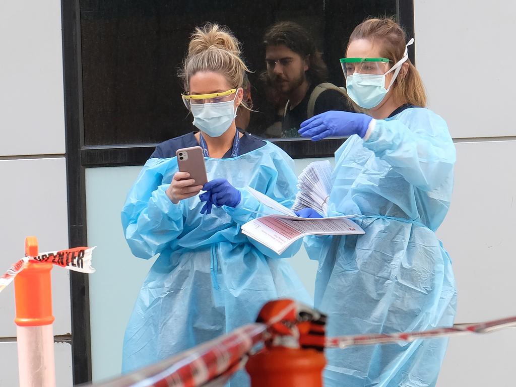 Hospital staff assist people waiting in line to be screened for COVID-19 outside the Royal Melbourne Hospital on March 11. Picture: Luis Ascui/Getty Images