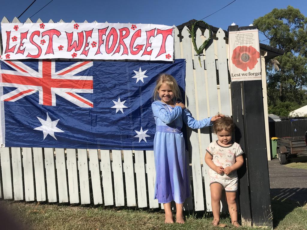 Asha Golledge, 4, and Isla Golledge, 1, of Shailer Park with the makeshift poster they created for Anzac Day. Picture: Jeni Faulkner