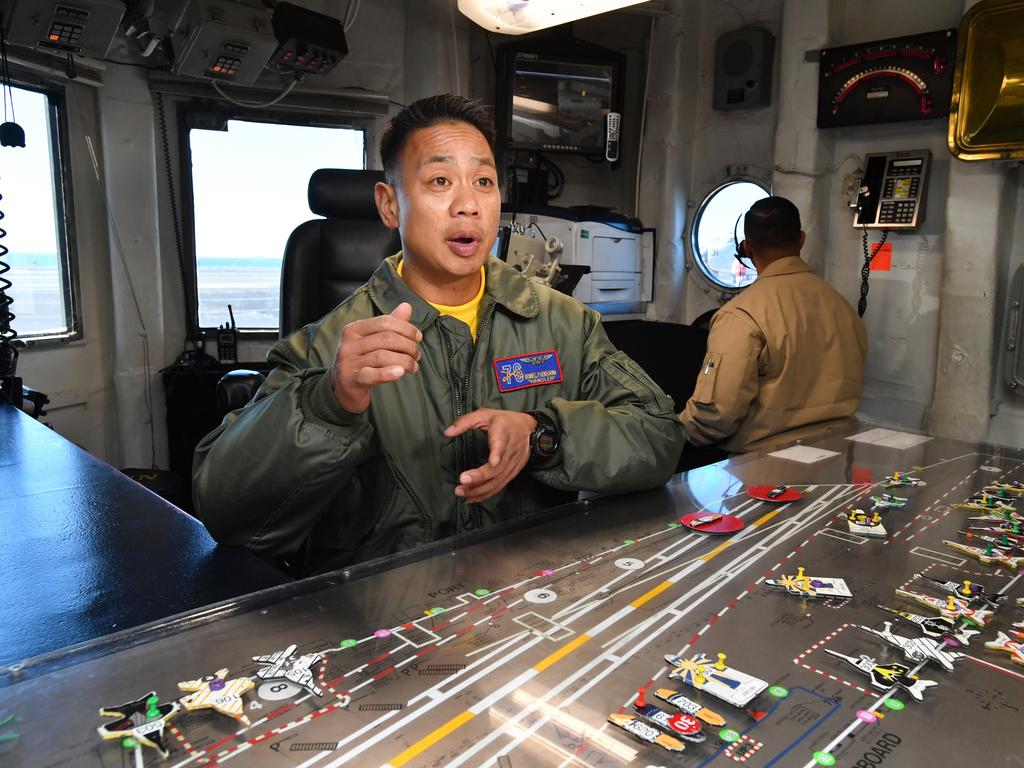 Flightdeck operator Rowell Venturina is seen organising figurines on a ‘ouija board’ on-board the USS Ronald Reagan. Picture: AAP Image/Darren England