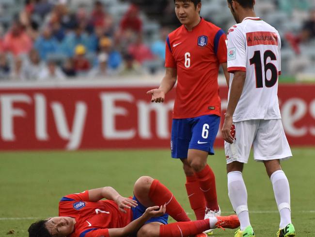 Son Heung Min goes down under a hefty Oman challenge.