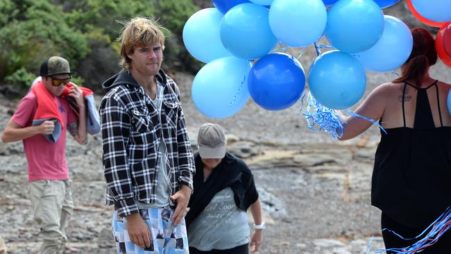 Girlfriend of missing fisherman Jesse Howes, Kaila Walker, walks past Jesse's brother Sam, left, and the friend who tried to rescue him as she heads down to where he was washed in the ocean. Picture by Peter Lorimer..