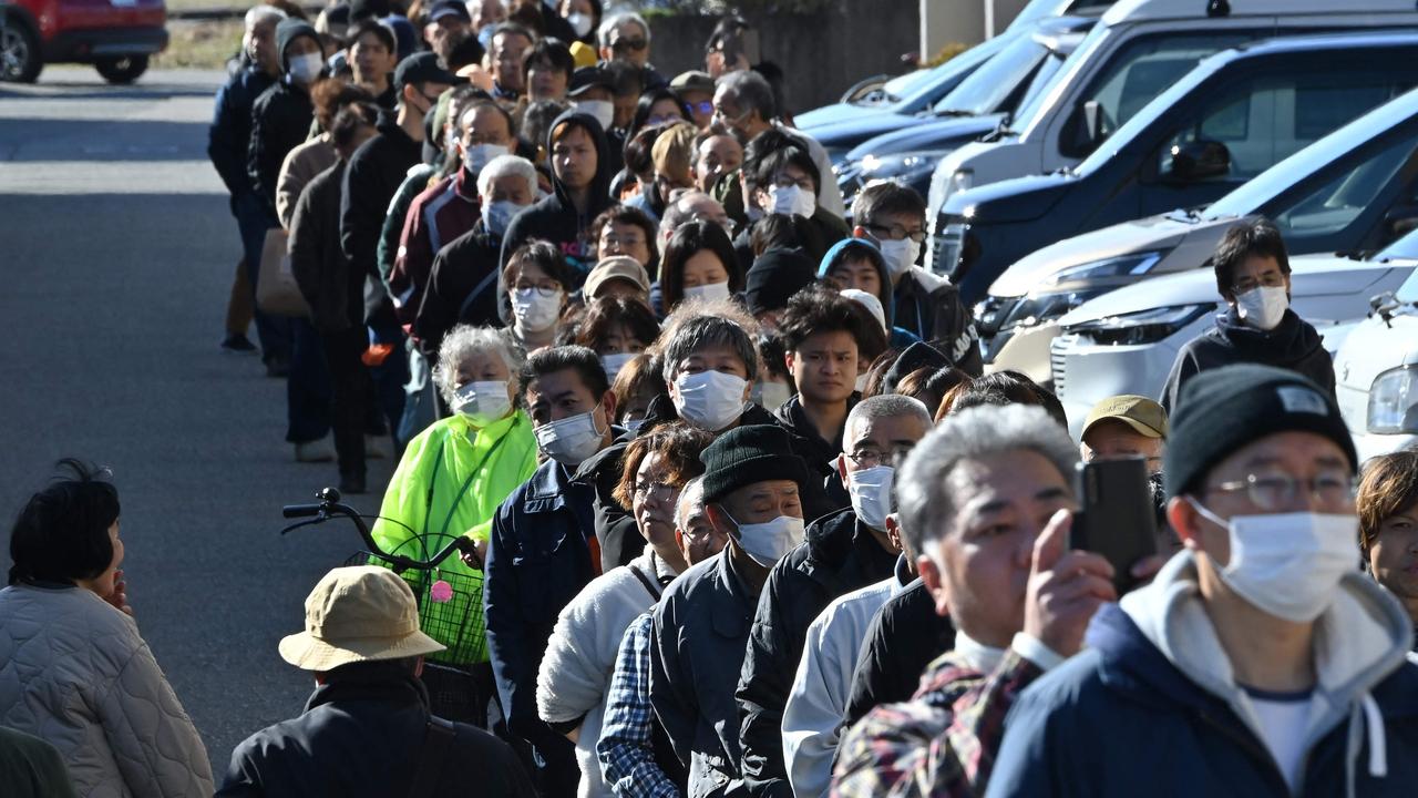 People queue around the Shika Town hall as they wait to receive water at a distribution point. Picture: Kazuhiro NOGI / AFP