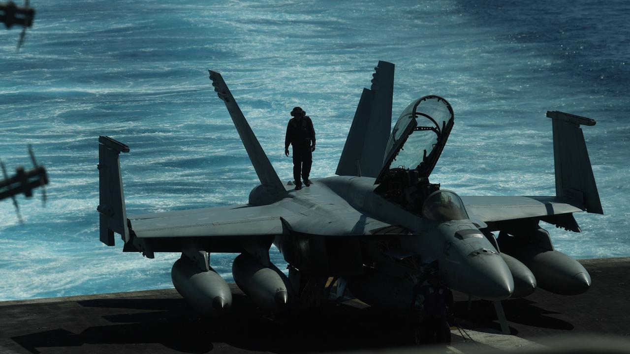 A sailor inspects atop an FA-18 hornet fighter jet during a routine training aboard US aircraft carrier Theodore Roosevelt in the South China sea on April 10, 2018. Picture: Ted Aljibe
