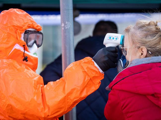 A Polish health official check the temperature of returning Poles crossing the Polish-German border from the eastern German town of Frankfurt (Oder) to Slubice on March 16, 2020, as measures are taken to slow down the spread of the novel coronavirus. - Polish Prime Minister Mateusz Morawiecki said Poland's borders would be closed to foreigners for 10 days, but that the government might prolong the shutdown. Two weeks of quarantine will also be imposed on people returning from abroad. (Photo by Odd ANDERSEN / AFP)