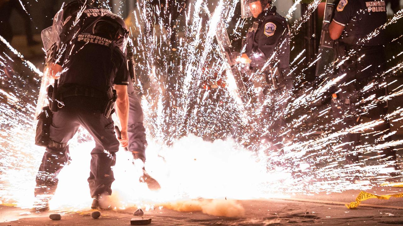 A firecracker thrown by protesters explodes under police one block from the White House on May 30 in Washington DC. Picture: AFP