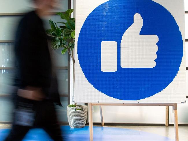 (FILES) This file photo taken on October 23, 2019 shows a Facebook employee walking past a sign displaying the "like" sign at Facebook's corporate headquarters campus in Menlo Park, California. - Facebook was branded "arrogant" and "unconscionable" for banning Australian users from sharing news on February 18, 2021, as its defiant response to government regulation inadvertently crippled the pages of several emergency services. (Photo by Josh Edelson / AFP)