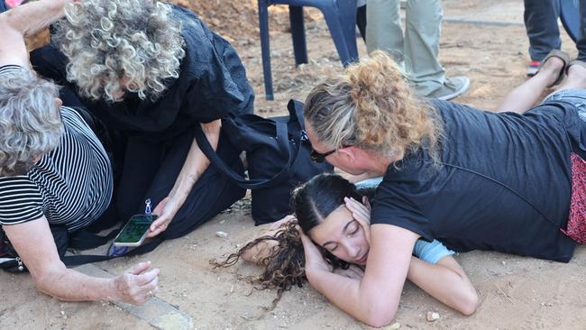 At a funeral for civilian Tom Godo, killed by Hamas in his Israeli kibbutz on October 12, mourners duck for cover as a rocket siren sounds. Picture: Gil Cohen-Magen / AFP