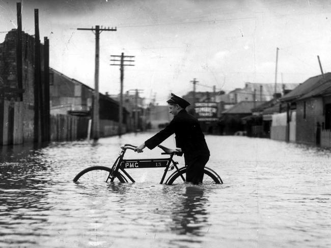 A postman braves a flooded Melbourne street in December 1934.