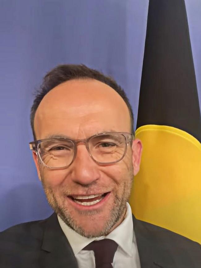 Adam Bandt in front of The Australian Aboriginal flag