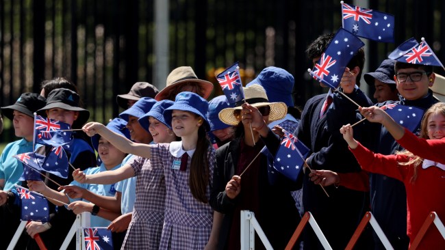 School children wave Australian flags as King Charles and Queen Camilla arrive in the ACT. Picture: Chris Jackson/Getty Images