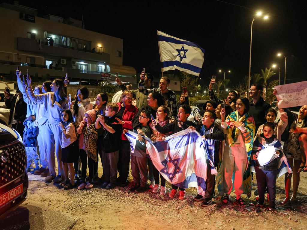 People cheer as a vehicle carrying hostages released by Hamas drives towards an army base in Ofakim, southern Israel, on November 26. Picture: AFP