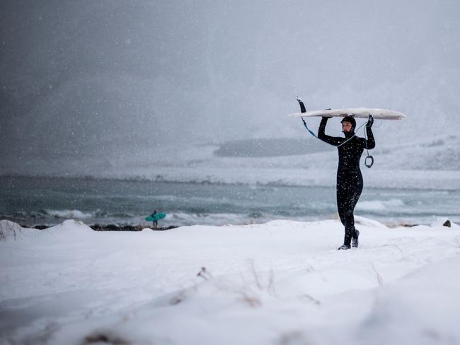 A surfer carries her surfboard as she walks out of the water under snowfall, on March 11, 2018, in Unstad, northern Norway, Lofoten islands, within the Arctic Circle. Picture: AFP