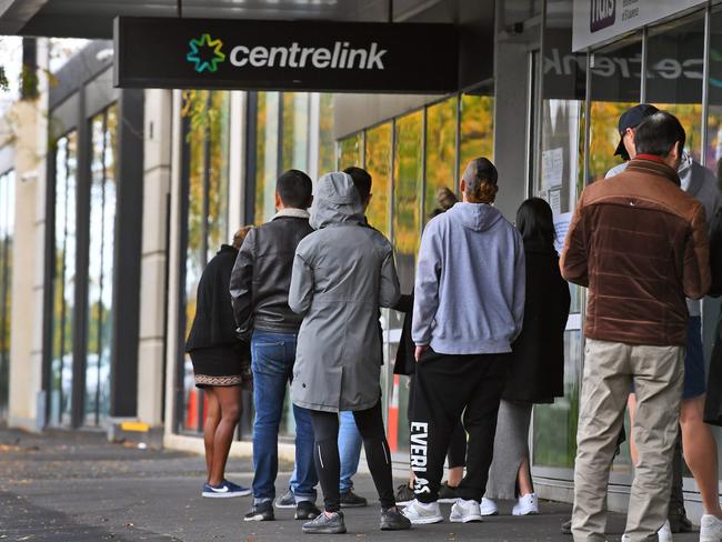 People queue up outside a Centrelink office in Melbourne on April 20, 2020, which delivers a range of government payments and services for retirees, the unemployed, families, carers and parents amongst others. - A report from the Grattan Institute predicts between 14 and 26 per cent of Australian workers could be out of work as a direct result of the coronavirus shutdown, and the crisis will have an enduring impact on jobs and the economy for years to come. (Photo by William WEST / AFP)