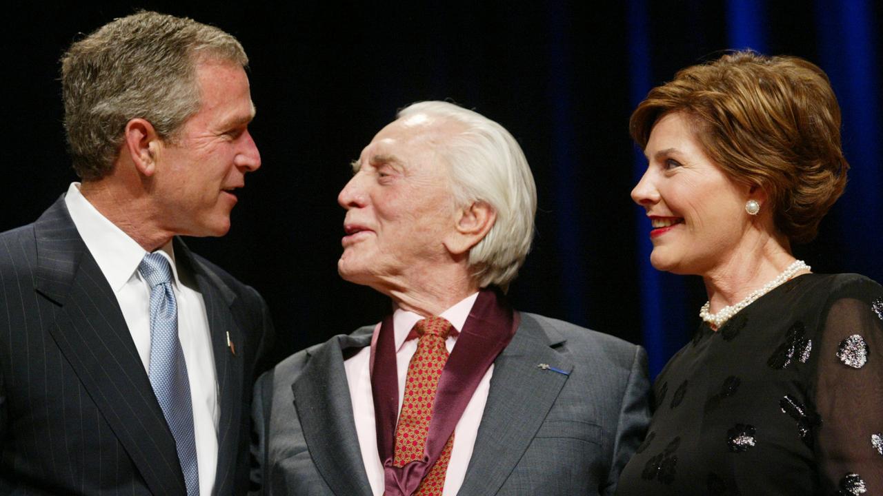 President George Bush, left, with actor Kirk Douglas, centre, as First Lady Laura Bush, right, looks on during the National Endowment for the Arts National Medal of Arts Awards ceremony in 2002.