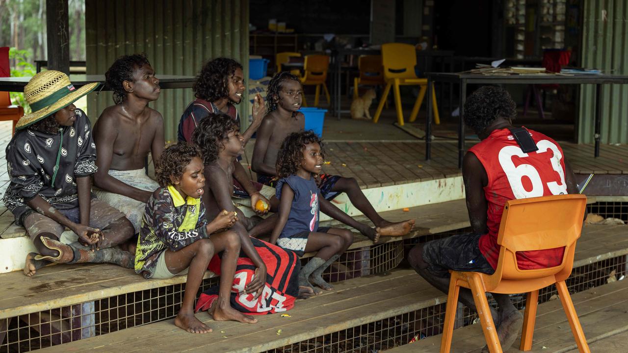 Children enjoying a story on the steps of Gamardi school. They sit outside because there is no electricity to power the classroom lights and fans. Picture: Rebecca Parker