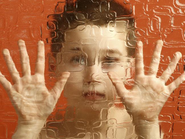 Generic image of a young boy showing palms, hand, behind a glass barrier.