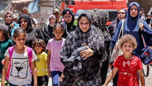A woman carries a child as she evacuates with others from the Tuffah neighbourhood in the east of Gaza City. Picture: AFP