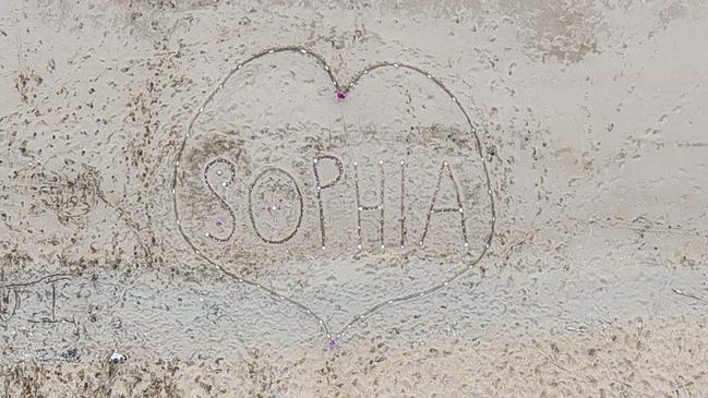 A message written in the sand at the community led vigil for Sophia Rose on Sunday. Attendees decorated the artwork with glow sticks and candles. Image: Zade Johnstone.