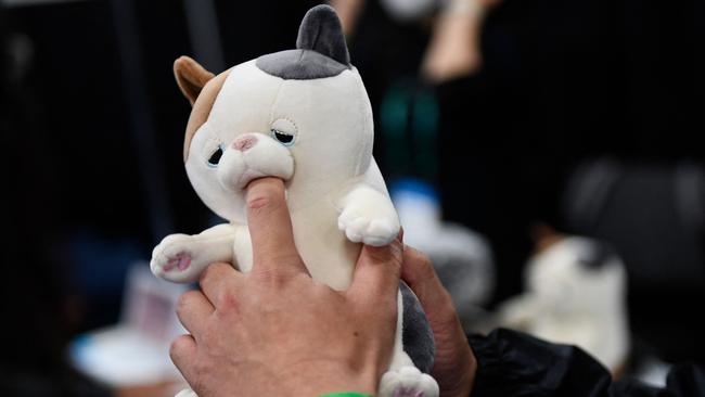 An attendee places a finger inside the mouth of Yukai Engineering Amagami Ham Ham play-biting cat robot during CES 2022. Picture: Patrick T. FALLON / AFP