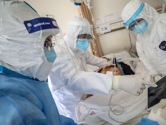 TOPSHOT - This photo taken on February 16, 2020 shows a doctor looking at an image as he checks a patient who is infected by the COVID-19 coronavirus at the Wuhan Red Cross Hospital in Wuhan in China's central Hubei province. - The death toll from the COVID-19 coronavirus epidemic jumped to 1,770 in China after 105 more people died, the National Health Commission said February 17. (Photo by STR / AFP) / China OUT