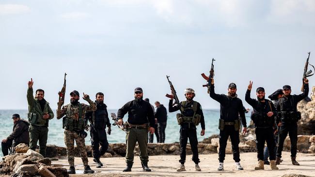 Security forces loyal to the interim Syrian government pose with firearms along a rocky beach by the Mediterranean Sea coast in Latakia. Picture: Omar Haj Kadour / AFP