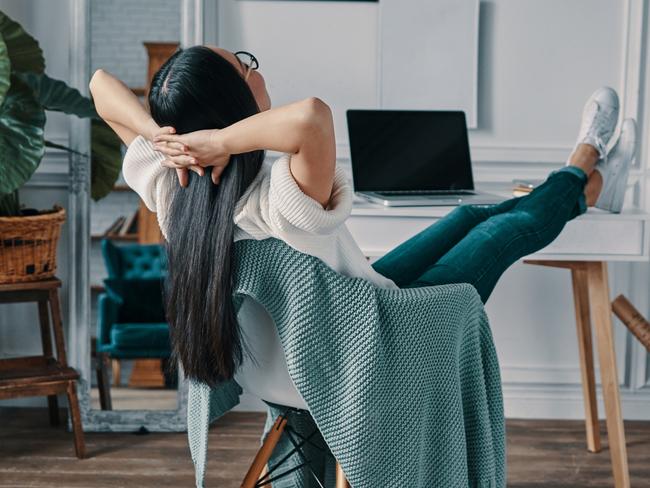 Rear view of young woman keeping hands behind head while sitting in home office