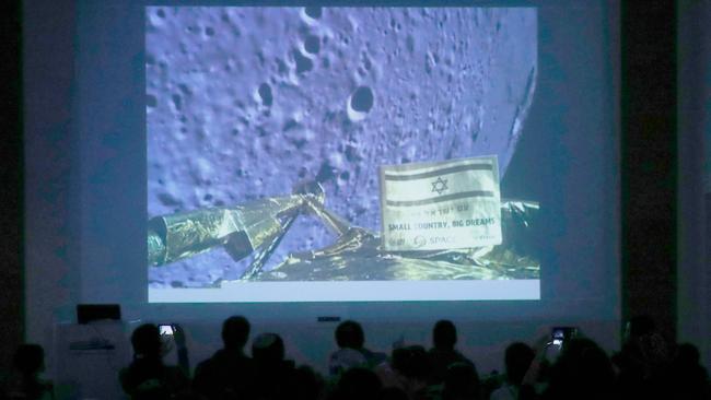 People watch a screen showing a picture taken by the camera of the Israel Beresheet spacecraft of the moon surface as the craft approaches and before it crashed. Picture: AFP