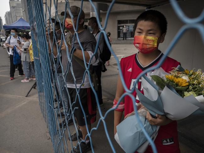 A boy holds flowers as he waits for students to emerge after finishing the final day of the National College Entrance Examination in Beijing, China. Picture: Getty Images