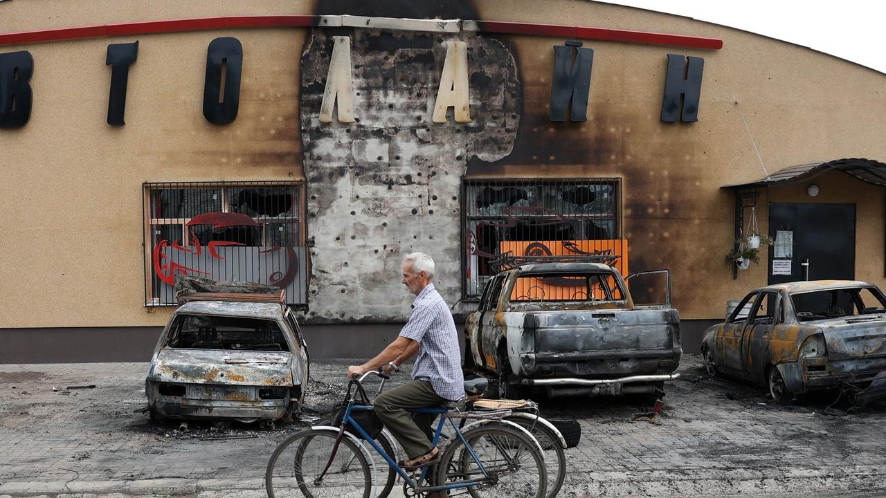 An elderly man riding a bicycle pushes the bike of his wife killed by a cluster bomb in Lyman, Donetsk region. Picture: AFP