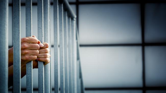 A prisoner behind the jail cell bars .