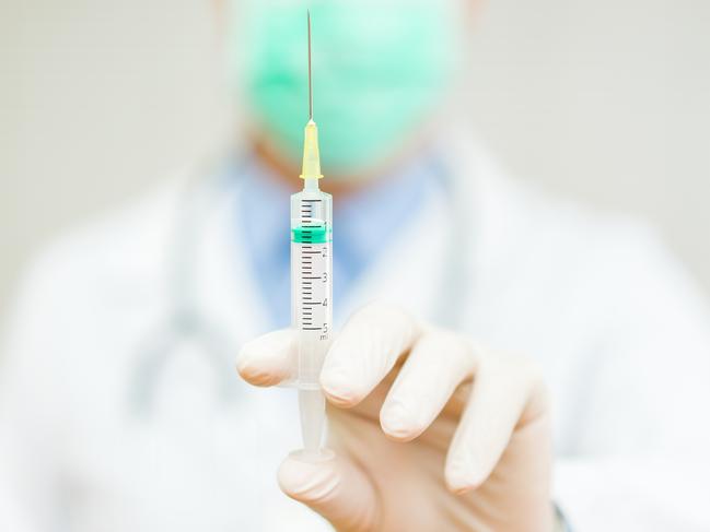 Doctor is holding an injection with needle with focus on injection