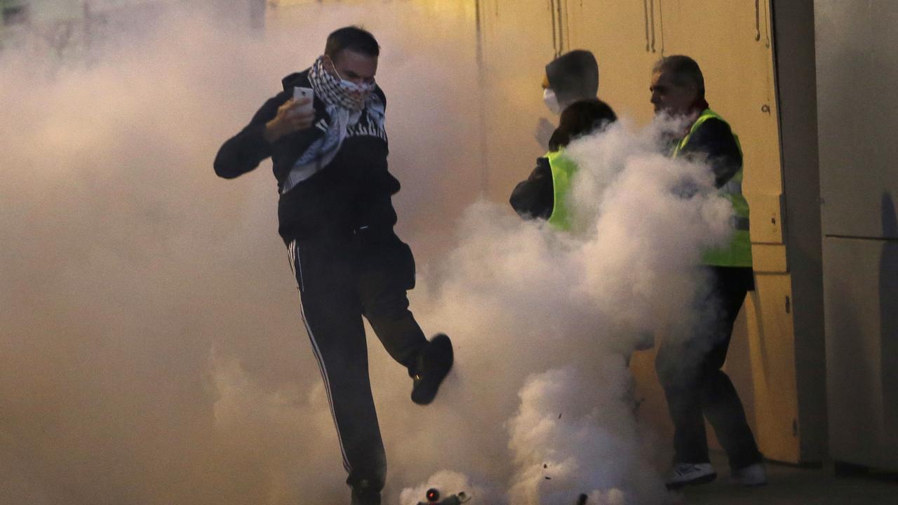 A demonstrator kicks a teargas canister away during clashes with police in Marseille. Picture: AP