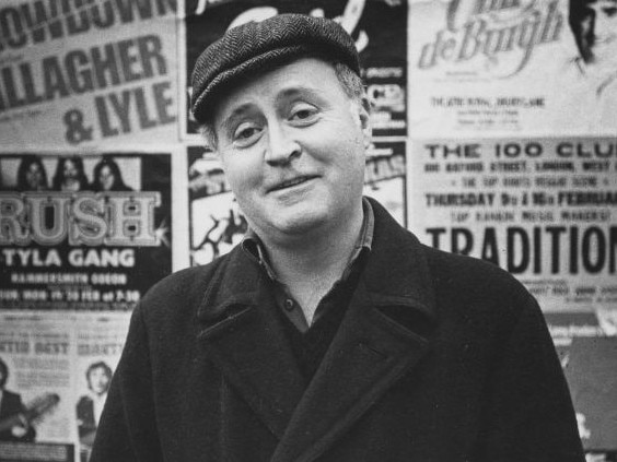 Portrait of playwright Edward Bond standing in front of a wall of posters, photographed for Radio Times in connection with the television drama 'Play of the Month - The Sea', 1978. First printed in Radio Times issue 2834, page 11, March 2nd 1978. (Photo by Chris Ridley/Radio Times/Getty Images)