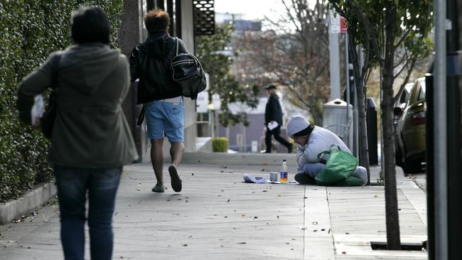 Homeless person sitting on the footpath in Campbell Street, Blacktown, trying to keep warm in the cold weather.