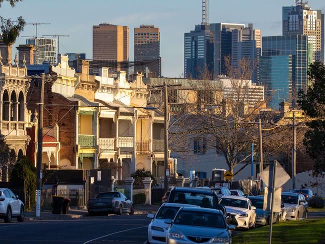 Winter afternoon in Fitzroy at Edinburgh Gardens with Victorian two story heritage houses against Melbourne high-rise CBD skyline, cars parked along suburban street. Picture: Jason Edwards