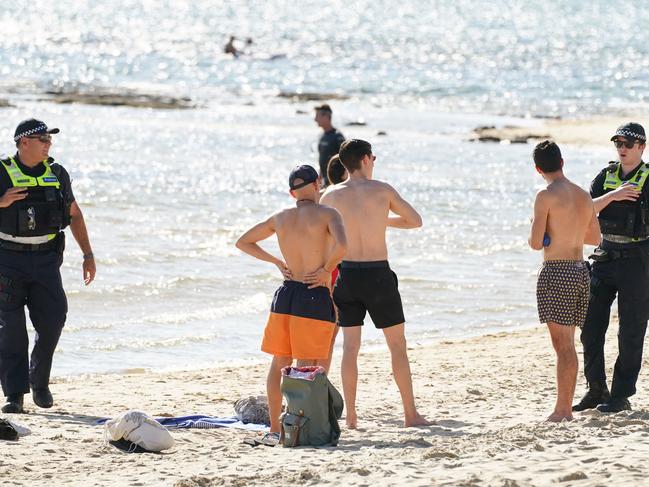 Police officers inform beachgoers that the beach is closed at Brighton Beach in Melbourne. Picture: AAP