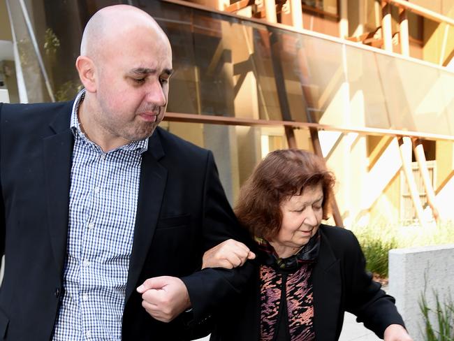 Vasko Stojanovski, Snezana’s brother in-law, guides his mum Pisana Stojanovska, her mother in-law behind an umbrella to avoid the camera as they leave court. Picture: Nicole Garmston