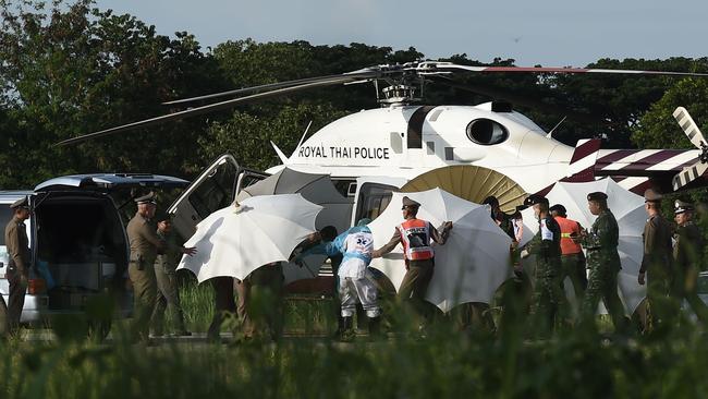 Police and military personnel use umbrellas to cover around a stretcher. Picture: AFP