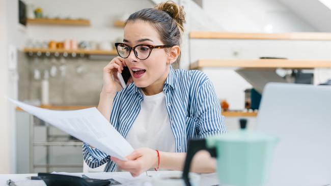 Upset woman talking on mobile phone and doing paper work