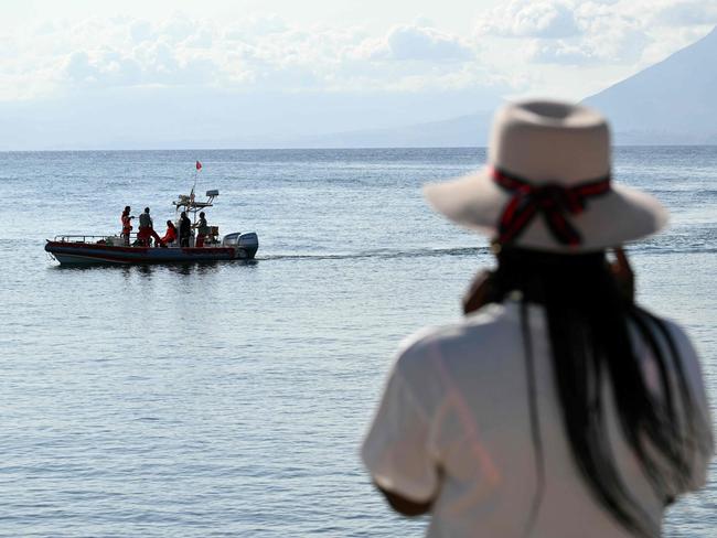 A woman watches rescue teams at work in Porticello near Palermo for the victims of a sunken superyacht. Picture: AFP