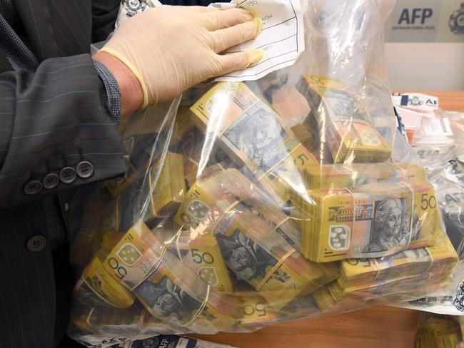 An Australian Federal Police officer displays some of the cash found after they smashed a massive fraud syndicate. Picture: AFP