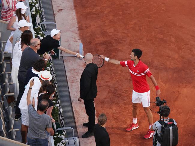 PARIS, FRANCE - JUNE 13: Tournament winner Novak Djokovic of Serbia passes his racquet to a fan as he celebrates after winning his Men's Singles Final match against Stefanos Tsitsipas of Greece during Day Fifteen of the 2021 French Open at Roland Garros on June 13, 2021 in Paris, France. (Photo by Adam Pretty/Getty Images)