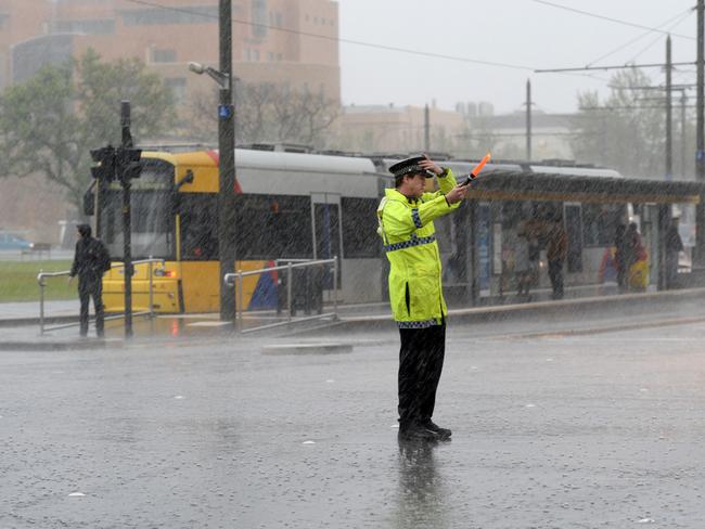 Police directing traffic at Victoria Square in belting rain with the traffic gone. Trams and trains have been hit by the outages. Picture: Greg Higgs