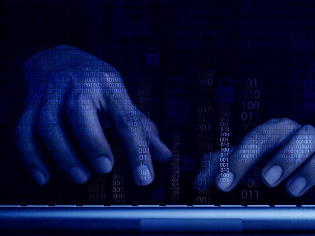 Cyberattack and internet crime, hacking and malware concepts. Digital binary code data numbers and secure lock icons on hacker' hands working with keyboard computer on dark blue tone background. Picture: iStock