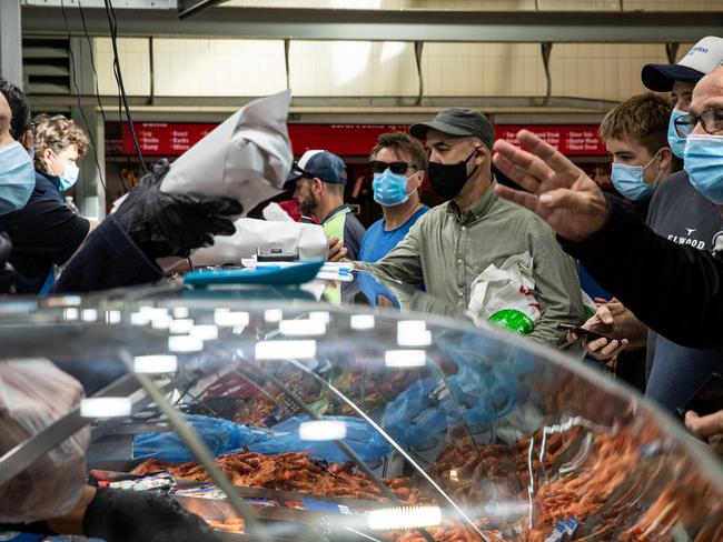 MELBOURNE, AUSTRALIA - DECEMBER 24: People shop for fish at the Queen Victoria Market on Christmas Eve on December 24, 2021 in Melbourne, Australia. Victoria has reintroduced rules for masks to be worn in indoor settings, as COVID-19 case numbers continue to rise.  From 11:59pm on Thursday 23 December, all Victorians aged 8 and up are required to wear a mask in all non-residential indoor settings. Masks must also be worn while moving around at major events attracting at least 30,000 people, but can be taken off by patrons while sitting down. (Photo by Diego Fedele/Getty Images)