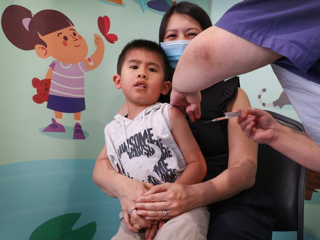 Lincoln, 5, sits on his mother’s lap to receive his first vaccination. Picture: David Caird