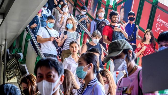 People with face masks arrive at a BTS Sky train station in Bangkok. Photo by Mladen ANTONOV / AFP