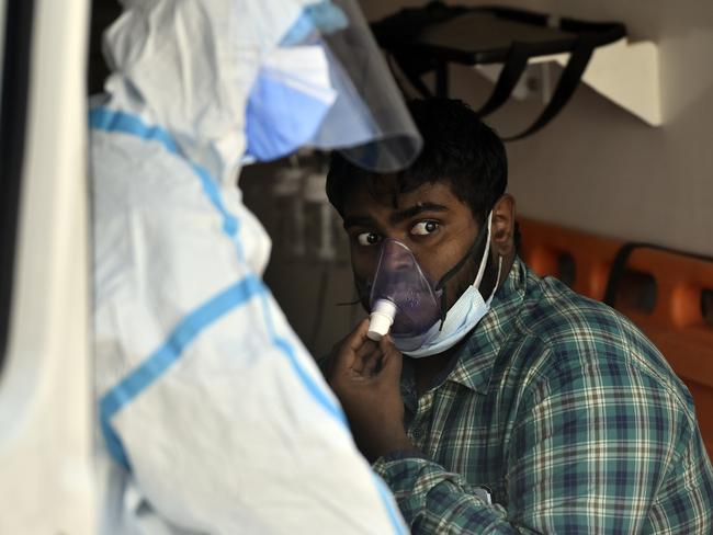 Health workers in PPE shift a patient to an isolation ward in New Delhi, India. Young people are increasingly dying. Picture: Sanjeev Verma/Hindustan Times via Getty Images